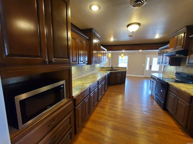 kitchen featuring decorative backsplash, dark brown cabinets, decorative light fixtures, light hardwood / wood-style flooring, and black electric range