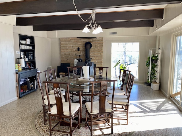 dining room with a wood stove and beamed ceiling