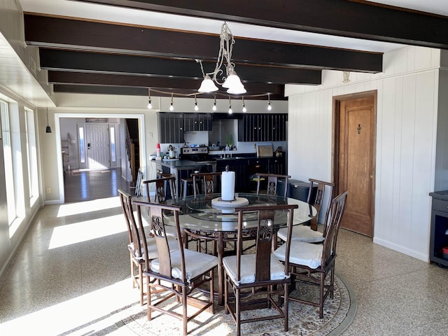 dining room featuring wood walls and beamed ceiling