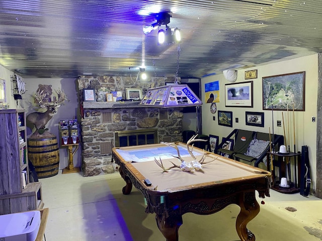 game room featuring billiards, a stone fireplace, and concrete flooring