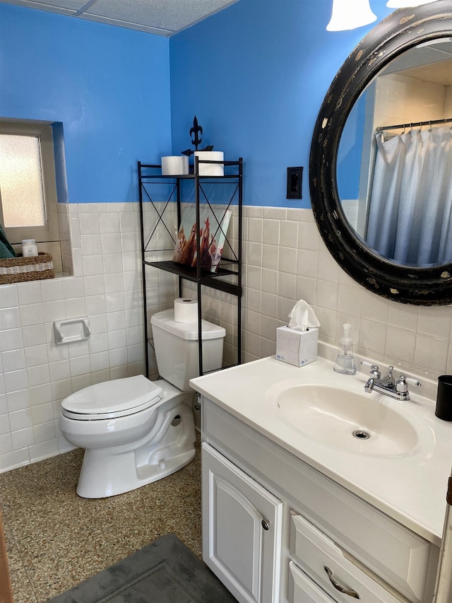 bathroom with tile walls, toilet, vanity, and walk in shower