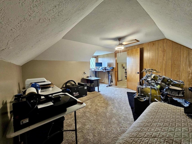 carpeted office with ceiling fan, a textured ceiling, vaulted ceiling, and wooden walls