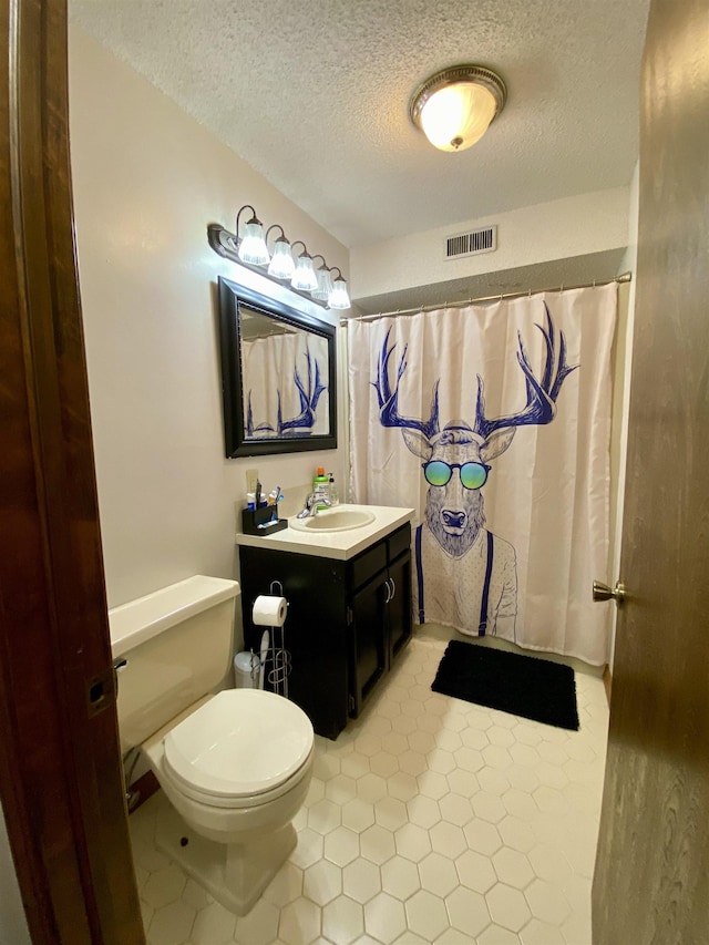 bathroom with a textured ceiling, toilet, vanity, and a shower with curtain