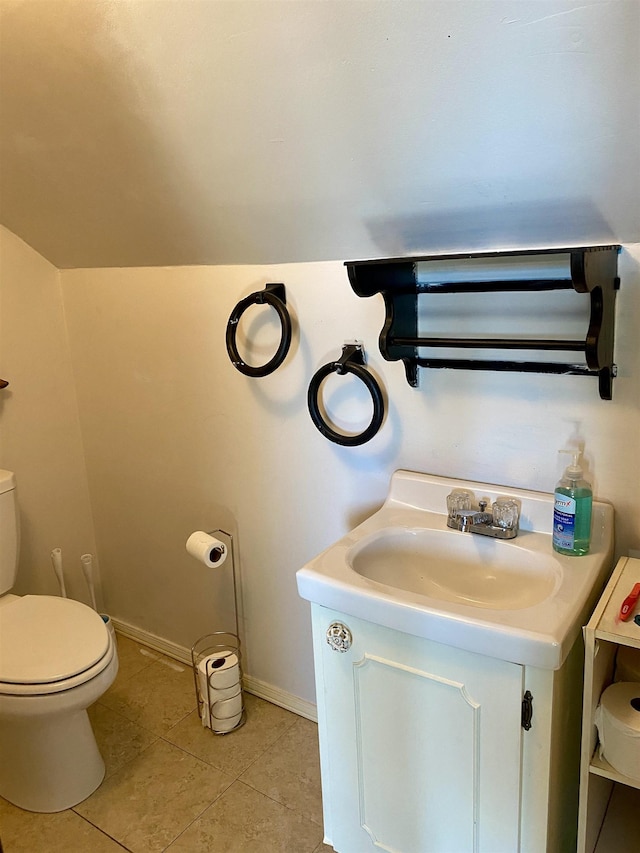 bathroom with vanity, toilet, tile patterned flooring, and lofted ceiling