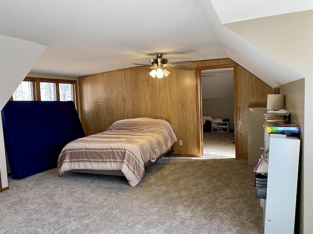 bedroom featuring ceiling fan, carpet, wooden walls, and vaulted ceiling