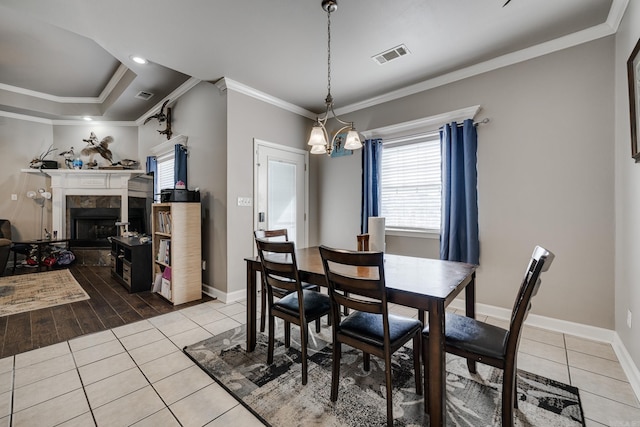 dining space with a tiled fireplace, crown molding, and tile patterned flooring