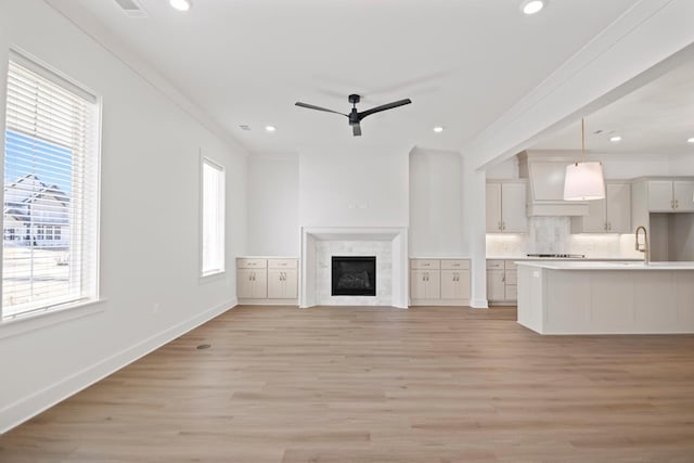 unfurnished living room featuring a wealth of natural light, crown molding, and light wood-type flooring