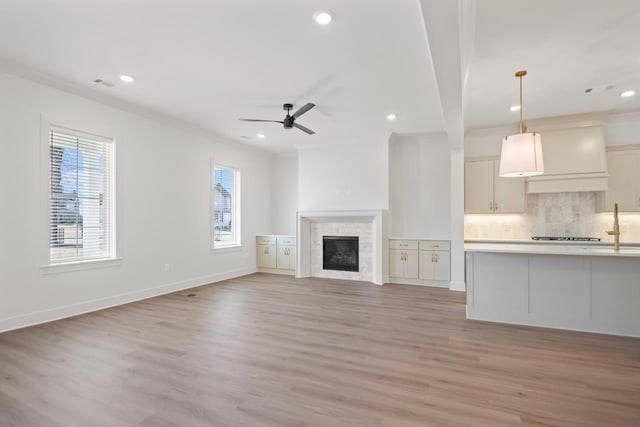 unfurnished living room featuring crown molding, light wood-type flooring, and ceiling fan