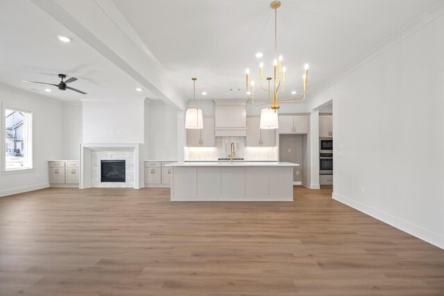 kitchen featuring sink, white cabinets, a kitchen island with sink, and pendant lighting