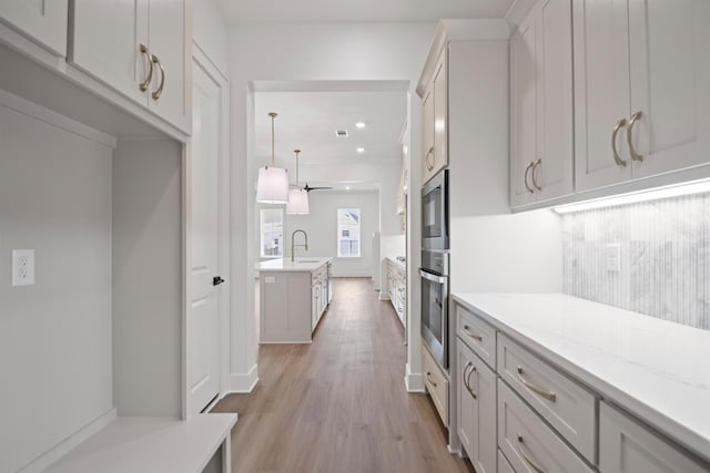 kitchen featuring appliances with stainless steel finishes, sink, backsplash, white cabinetry, and light stone countertops