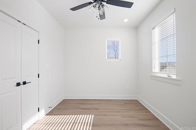 interior space with ceiling fan, multiple windows, a closet, and light wood-type flooring