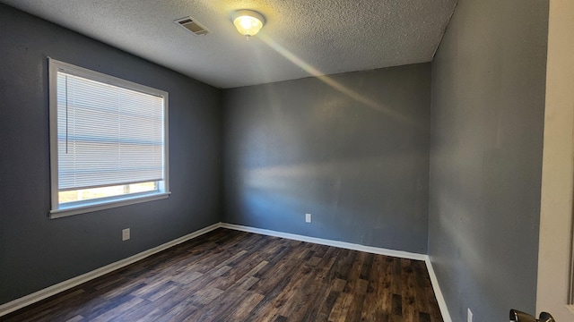 spare room with a textured ceiling and dark hardwood / wood-style floors