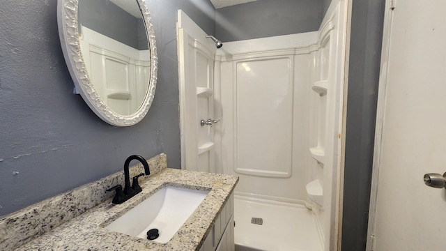 bathroom featuring walk in shower and vanity