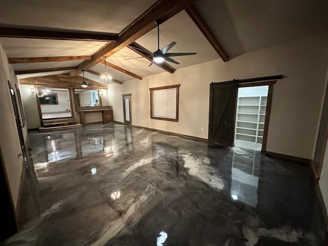 empty room featuring lofted ceiling with beams, ceiling fan, and a barn door