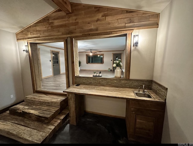 bathroom featuring ceiling fan, sink, wood walls, and vaulted ceiling with beams