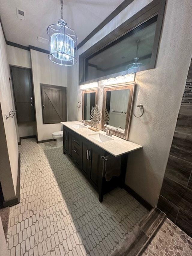 bathroom featuring ceiling fan with notable chandelier, toilet, vanity, and ornamental molding