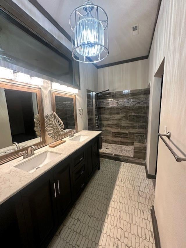 bathroom with ornamental molding, tiled shower, a notable chandelier, and vanity