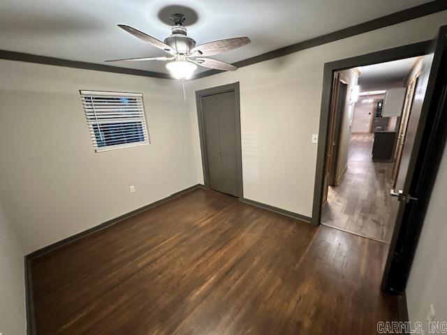 unfurnished bedroom with dark wood-type flooring, a closet, ceiling fan, and ornamental molding