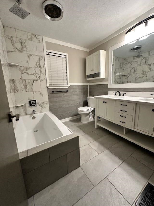 bathroom featuring a textured ceiling, tile patterned floors, vanity, tile walls, and toilet