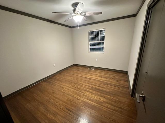 unfurnished bedroom featuring ceiling fan, dark hardwood / wood-style floors, and crown molding