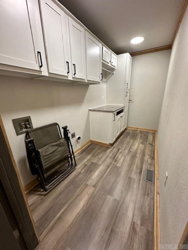 washroom with washer hookup, light hardwood / wood-style flooring, ornamental molding, and cabinets