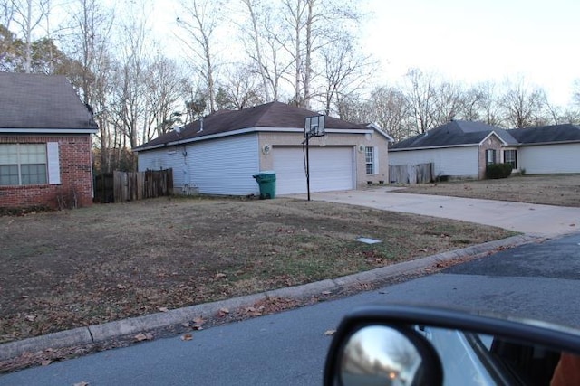 view of side of property with a garage, fence, concrete driveway, and an outbuilding