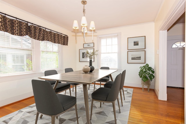 dining room with a healthy amount of sunlight, ornamental molding, a chandelier, and light wood-type flooring