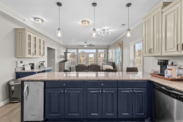 kitchen featuring stainless steel appliances, cream cabinets, and decorative light fixtures