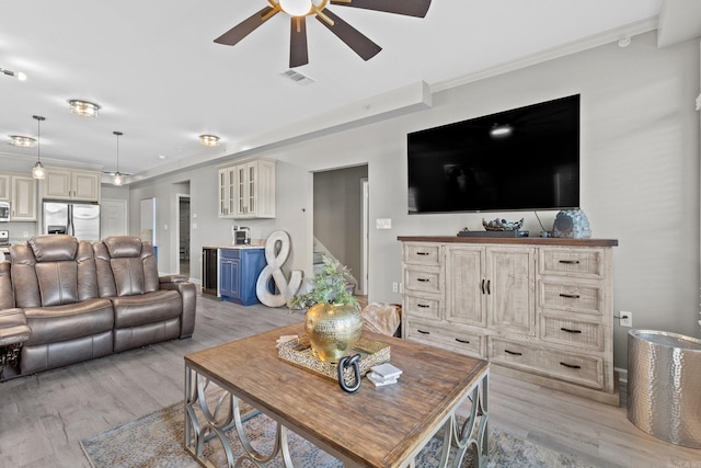 living room featuring light hardwood / wood-style flooring, ornamental molding, and ceiling fan