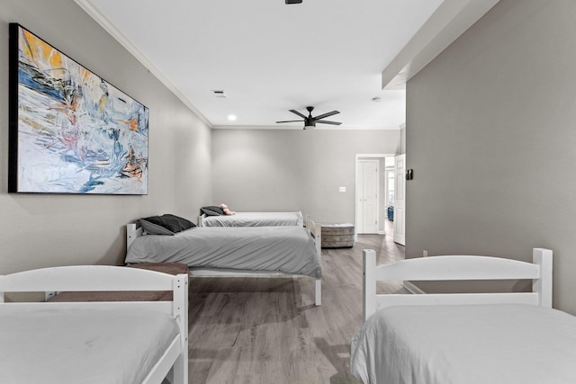 bedroom featuring crown molding, wood-type flooring, and ceiling fan