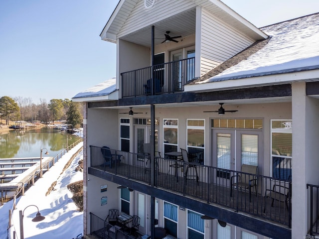 back of property with a water view, a balcony, and ceiling fan