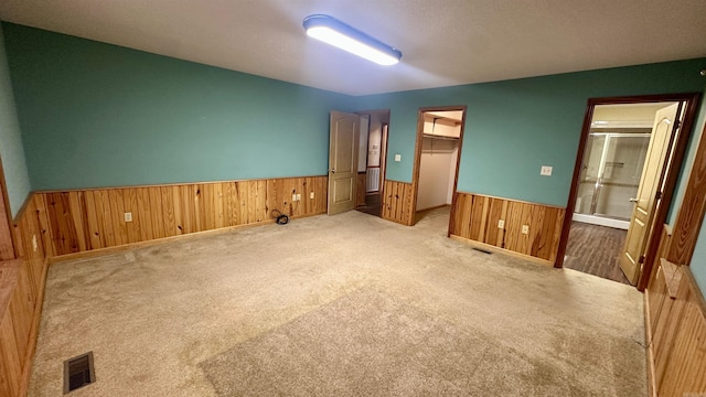 unfurnished bedroom with light carpet, a walk in closet, a closet, and ensuite bathroom