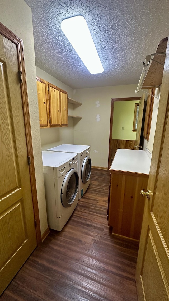 clothes washing area featuring cabinets, washing machine and dryer, a textured ceiling, and dark hardwood / wood-style flooring