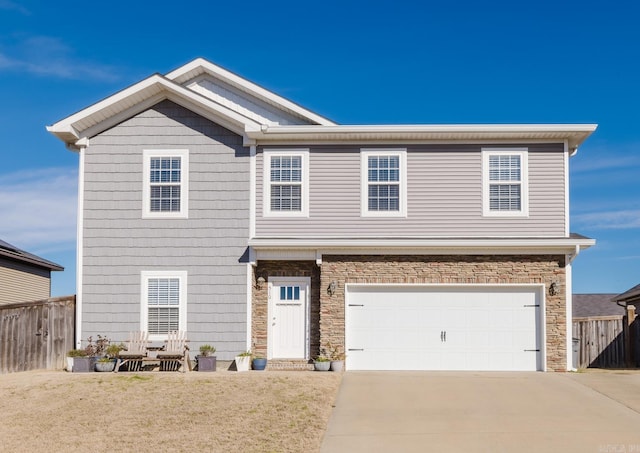 view of front of property featuring an attached garage, fence, stone siding, and driveway