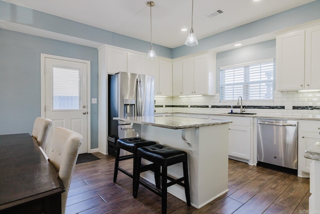 kitchen with appliances with stainless steel finishes, dark hardwood / wood-style flooring, a center island, and sink