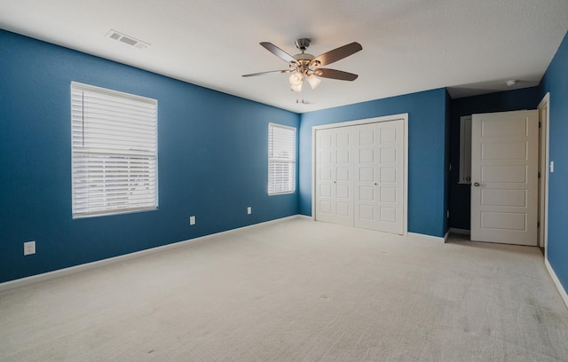 unfurnished bedroom with light colored carpet, ceiling fan, and a closet