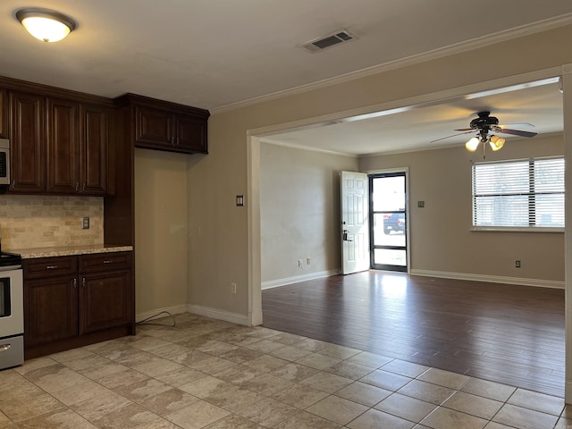 kitchen featuring dark brown cabinetry, crown molding, tasteful backsplash, appliances with stainless steel finishes, and ceiling fan