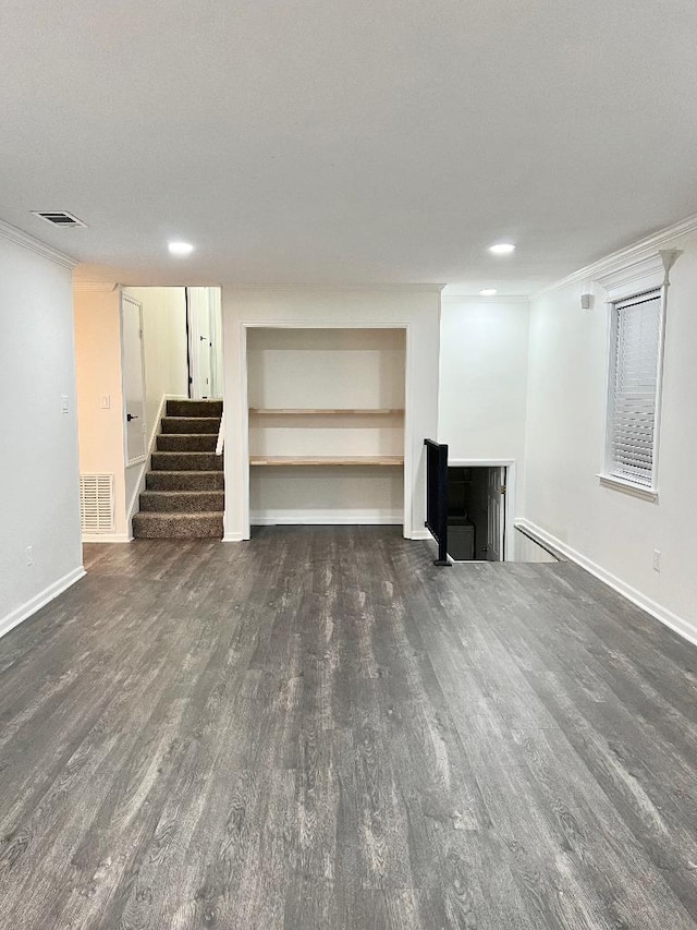 basement with crown molding, dark wood-type flooring, and built in shelves