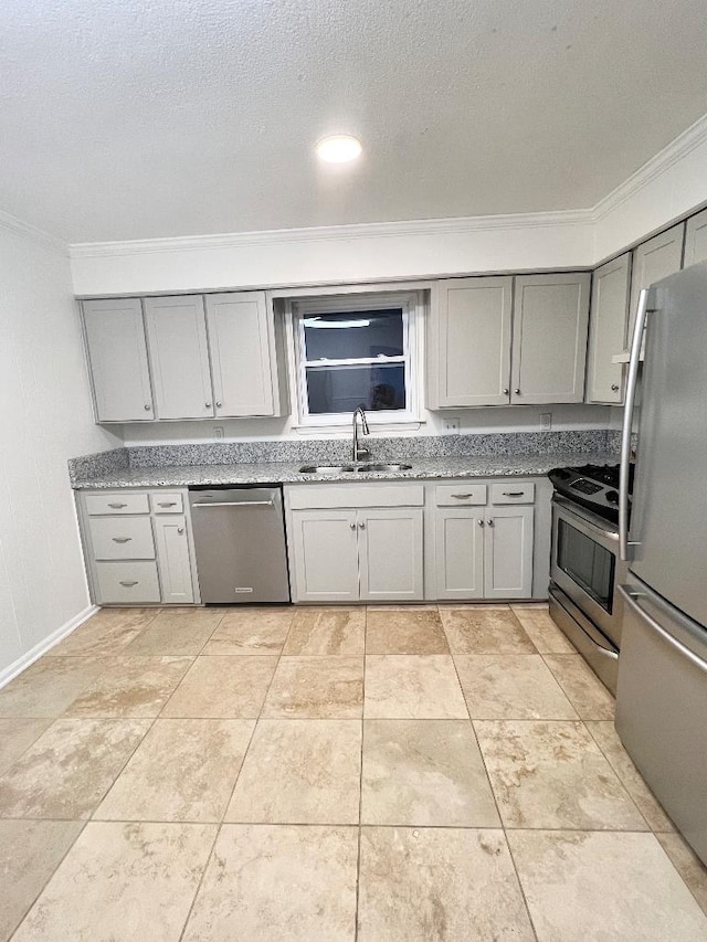 kitchen with sink, a textured ceiling, ornamental molding, appliances with stainless steel finishes, and gray cabinets