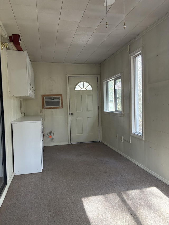 foyer entrance featuring a wall mounted air conditioner and dark colored carpet