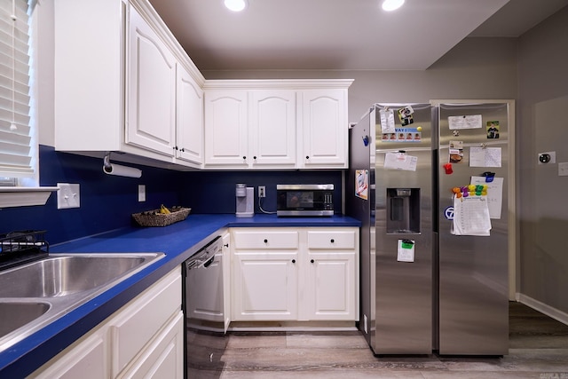 kitchen with stainless steel appliances, white cabinetry, and light hardwood / wood-style flooring