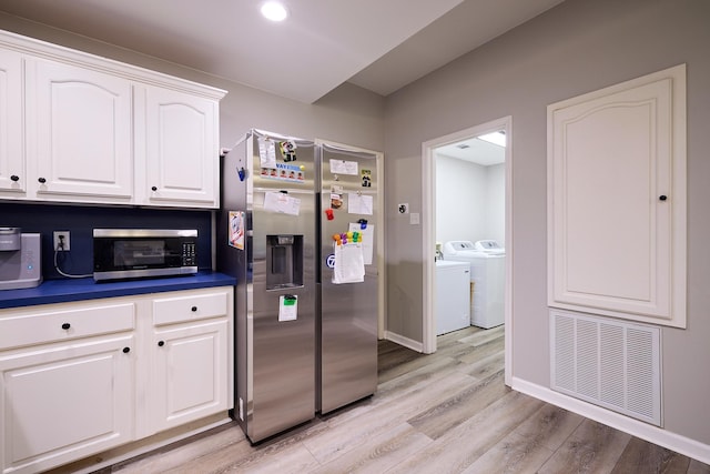 kitchen with white cabinetry, appliances with stainless steel finishes, washer and dryer, and light wood-type flooring