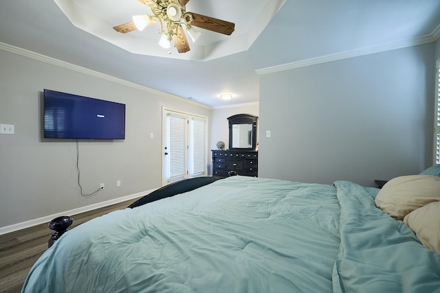 bedroom featuring dark wood-type flooring, ceiling fan, ornamental molding, and a raised ceiling