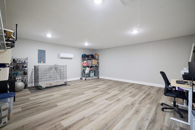 office space with electric panel, a wall unit AC, and light wood-type flooring