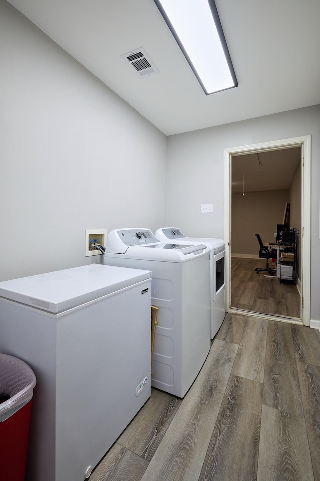 laundry room with hardwood / wood-style flooring and washer and dryer