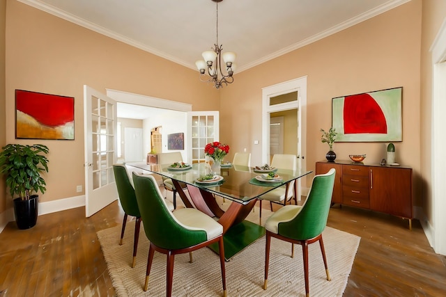 dining area with dark wood-type flooring, ornamental molding, an inviting chandelier, and french doors