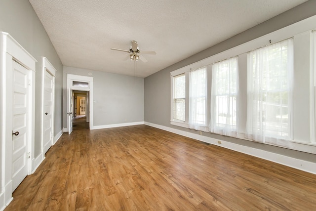 empty room with hardwood / wood-style flooring, ceiling fan, and a textured ceiling