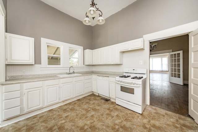 kitchen featuring white appliances, sink, hanging light fixtures, and white cabinets