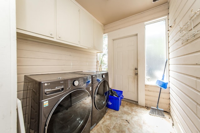 laundry area featuring washer and dryer, wooden walls, and cabinets