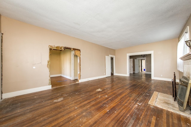 unfurnished living room featuring a fireplace, dark hardwood / wood-style floors, and a textured ceiling